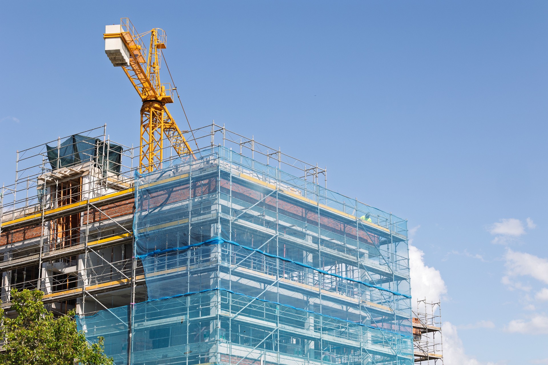 Building under construction with scaffolding and crane on a sunny day