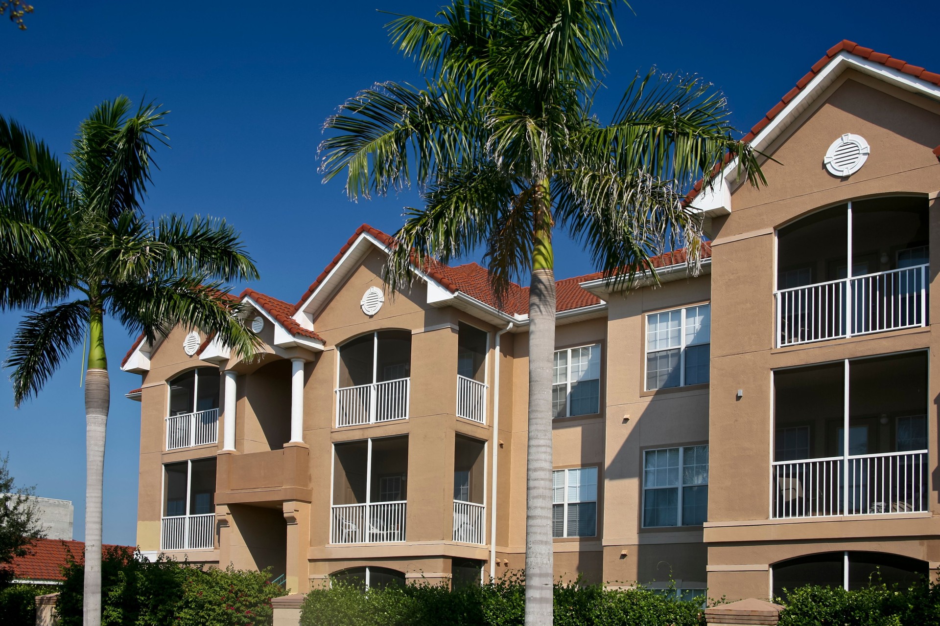 Exterior of a beige condominium building with palm trees