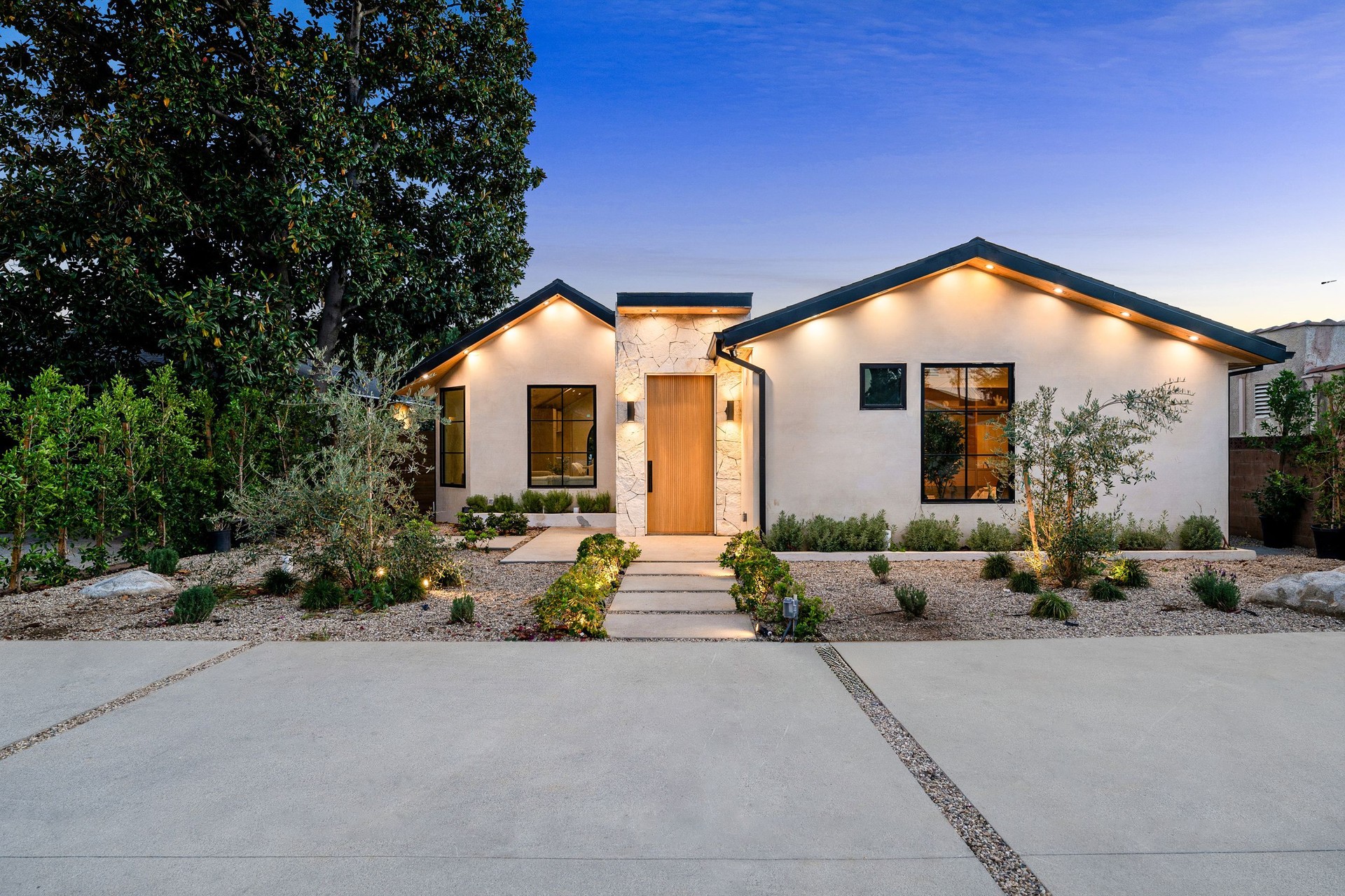 Modern single-story house with landscaped yard at dusk.